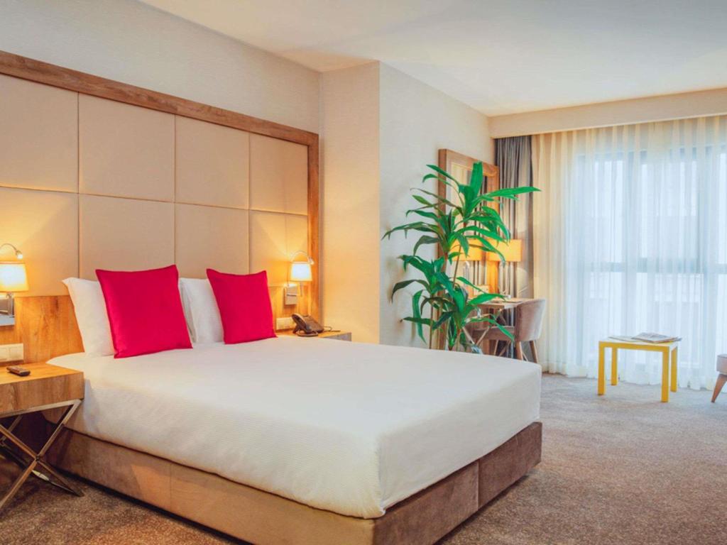 a large bedroom with a large bed with red pillows at ibis Styles Istanbul Bomonti in Istanbul