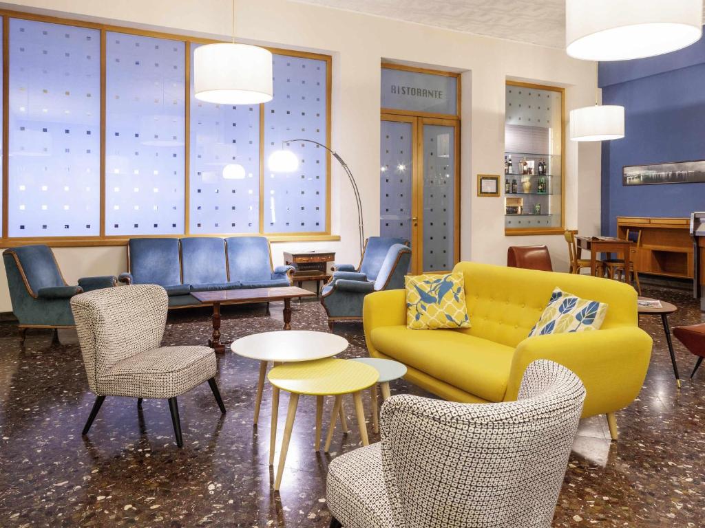 eine Lobby mit einem gelben Sofa und Stühlen und Tischen in der Unterkunft ibis styles Trani in Trani