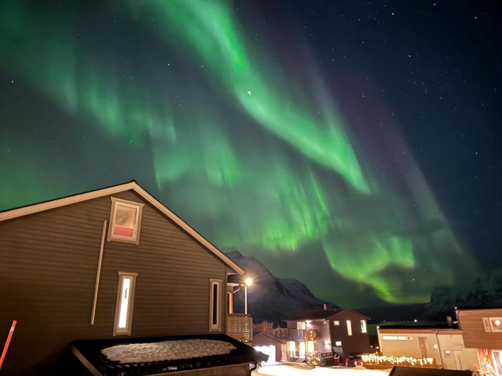 een huis met het noorderlicht in de lucht bij Ersfjord Villa Apt in Tromsø
