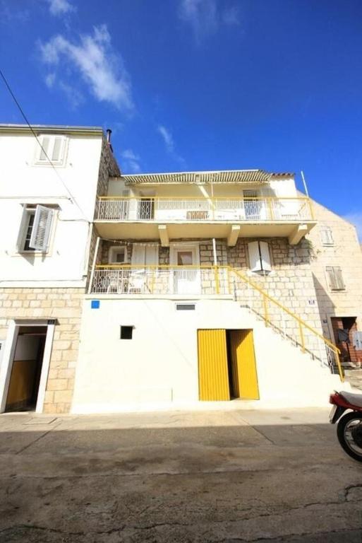 a white building with yellow doors on the side of it at Apartments Mat in Vis