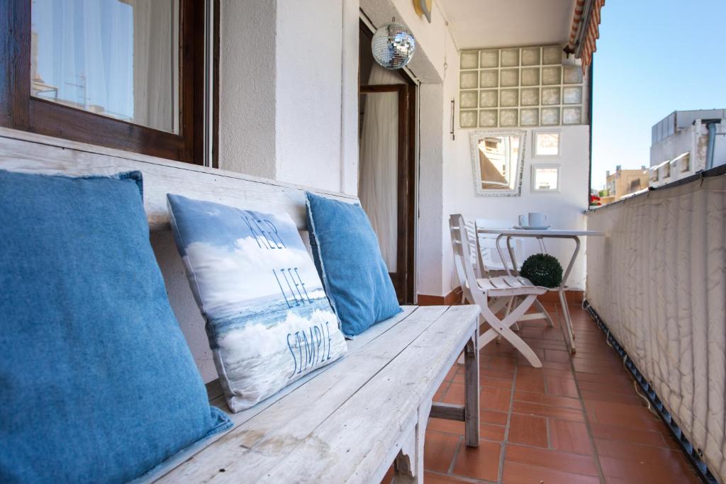 un banco de madera con almohadas azules en el balcón en Du Soleil Apart, en Sitges