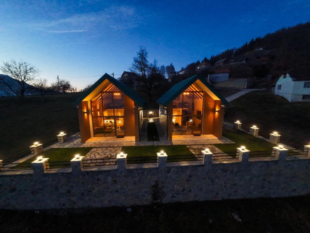 a large wooden house with lights in the night at Vista Village in Mojkovac