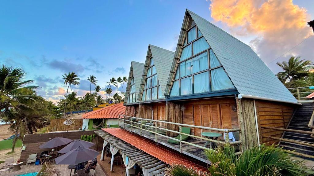 a house with a gambrel roof on a beach at Pousada Beach House Coqueirinho in Jacumã