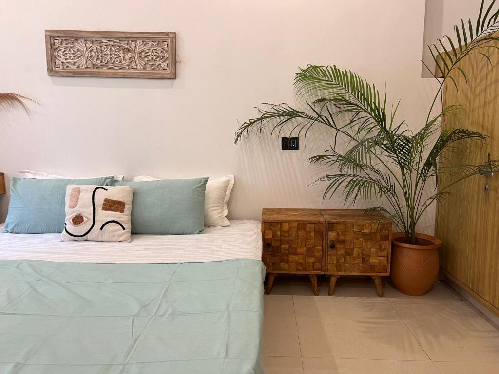een slaapkamer met een bed met kussens en een plant bij Prithvi Hotel - Aesthetic Quite Rooms In Upper Tapovan with free airport pickup for 7 or more nights booking in Rishīkesh