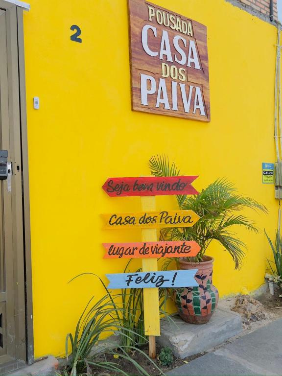 a sign in front of a yellow wall with signs at Pousada - Casa dos Paiva in Barreirinhas