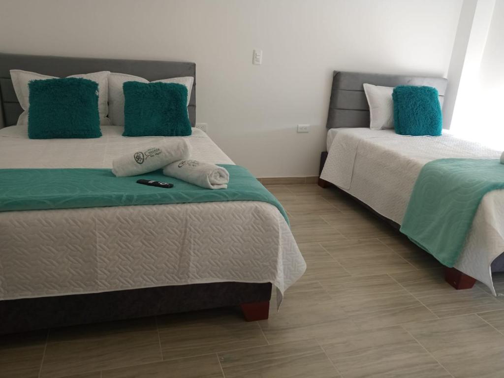1 Schlafzimmer mit 2 Betten und grüner und weißer Bettwäsche in der Unterkunft Cabañas hotel COLONIA SAN MIGUEL in Paipa