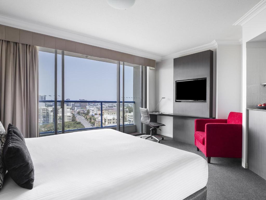 een hotelkamer met een groot bed en een rode stoel bij Mantra on Queen in Brisbane