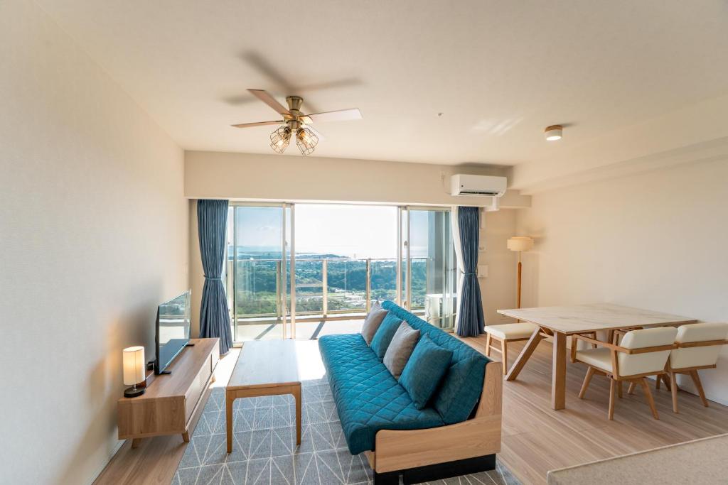 een woonkamer met een blauwe bank en een tafel bij KAI Okinawa in Kitanakagusuku