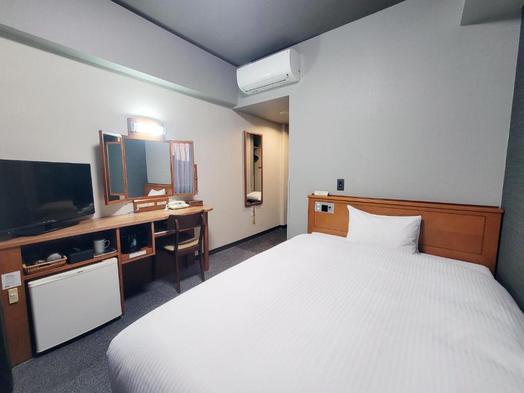 a hotel room with a bed and a television at Hotel Route-Inn Fujieda-Eki Kita in Fujieda