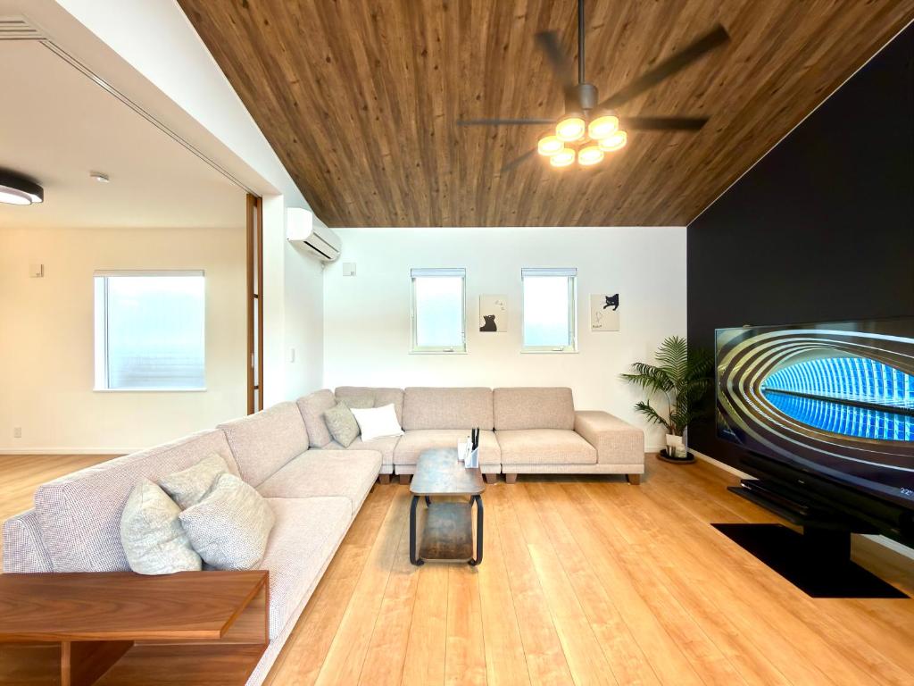 a living room with a couch and a tv at Futtsu Pool Villa A&F -富津プールヴィラ A&F- in Futtsu
