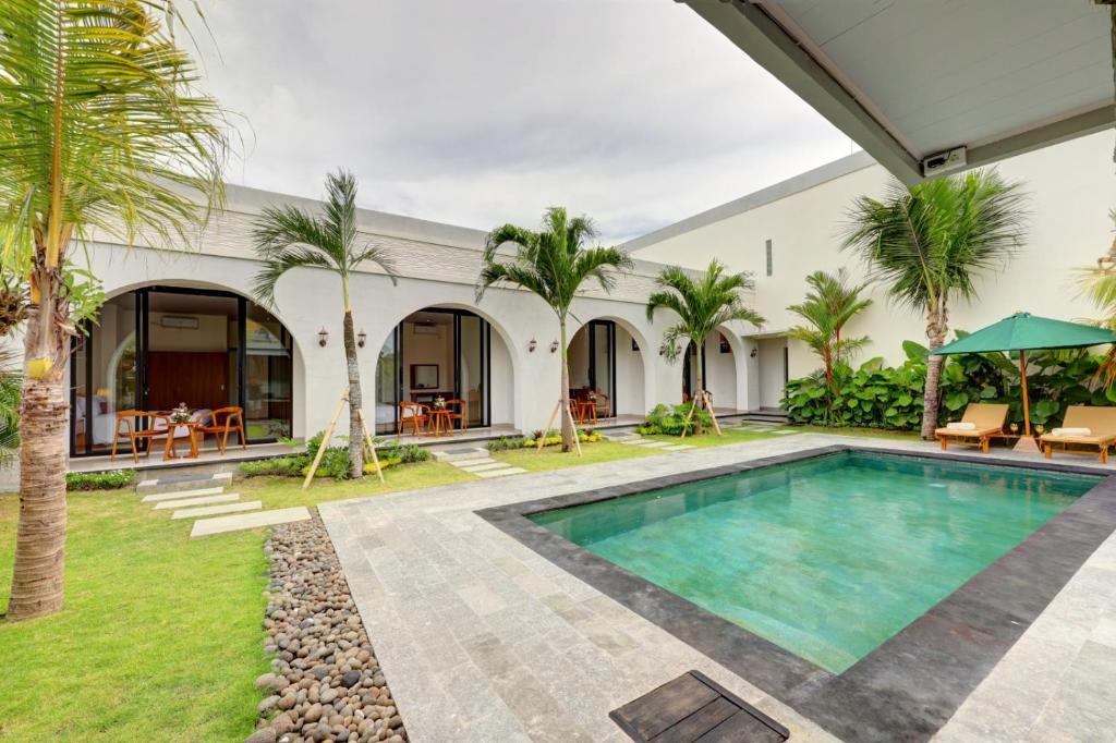 einen Außenpool mit Palmen und ein Haus in der Unterkunft Close to Beach Paddy View 6BR Villa with Billiard in Tanah Lot