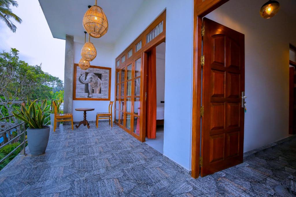 a hallway with a wooden door and a table and chairs at Happy Corner Ahangama in Midigama West