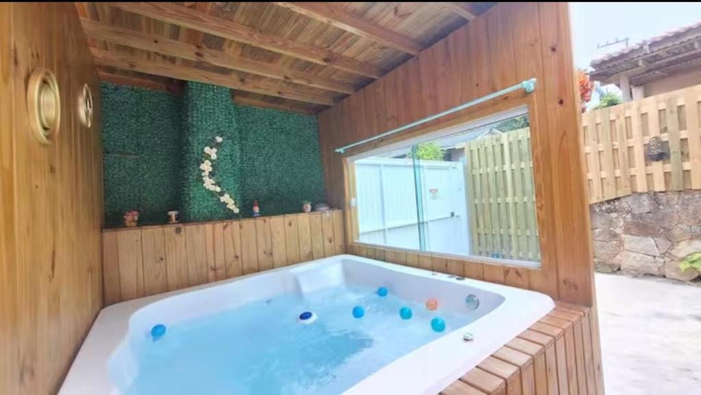 a large bath tub in a wooden room with a window at Casa com jacuzzi in Florianópolis
