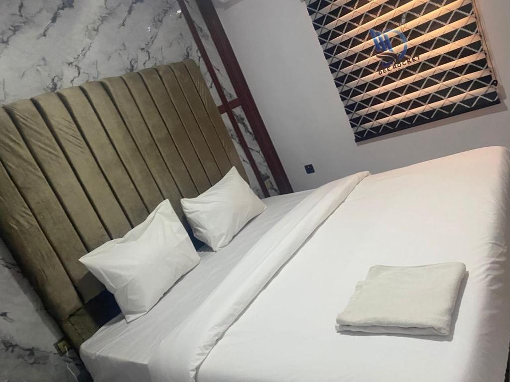 a white bed with two pillows on top of it at Dee Rocket Hotel & Lounge in Ibadan