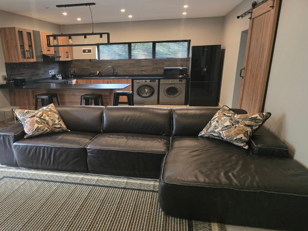 a leather couch in a living room with a kitchen at Crane's Nest - Luxury Ground in Pretoria