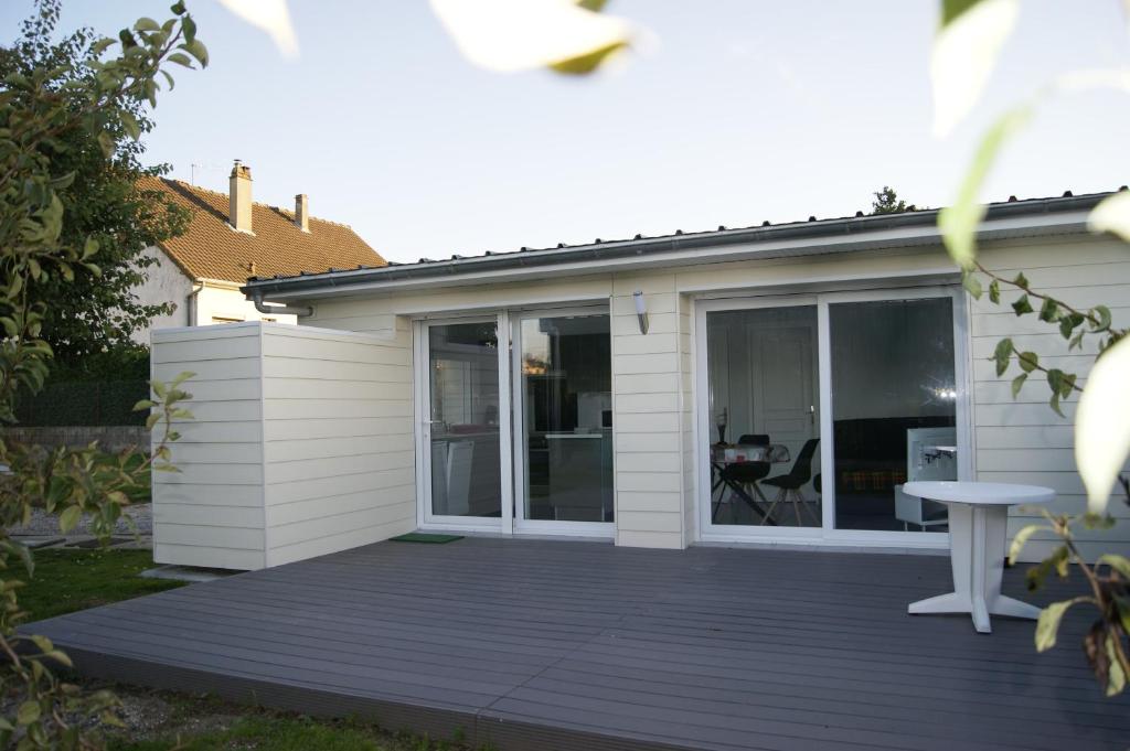 een huis met een houten terras met een tafel bij Le Tiot Gîte in Le Bois de Cise