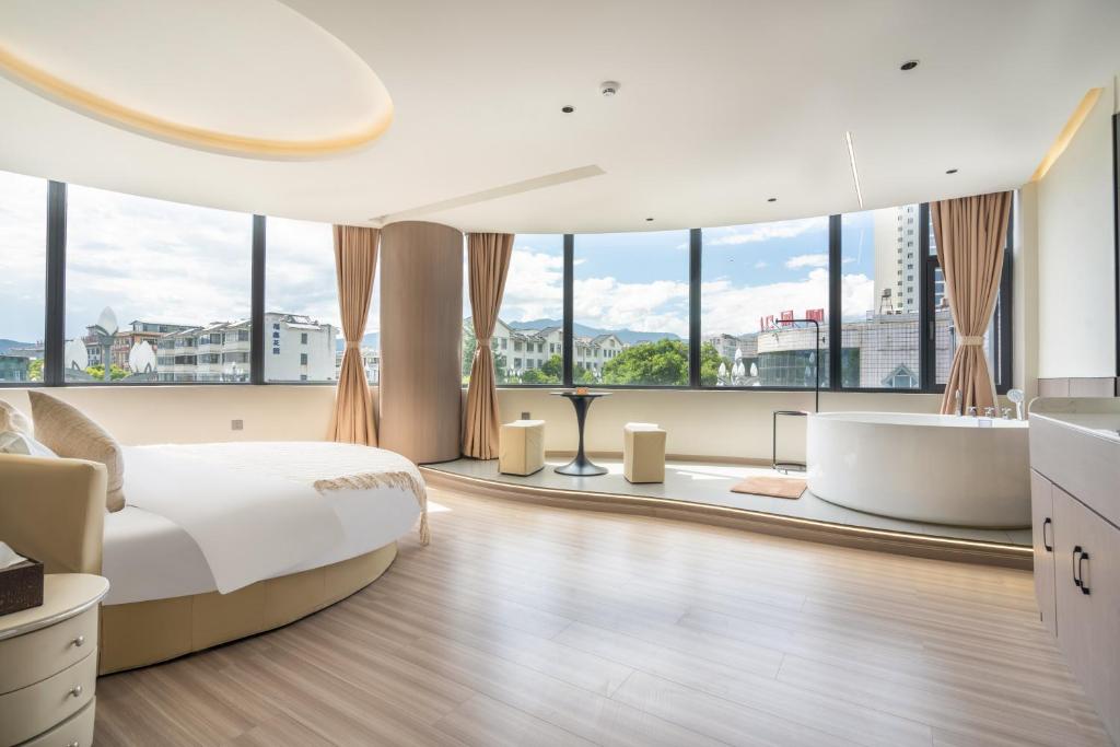 a bedroom with a large bed and a tub and windows at Ancient City District Ai Shan Hotel in Lijiang