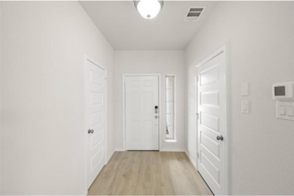 een witte gang met witte deuren en houten vloeren bij Luxury 6 Bedroom Home in Denton