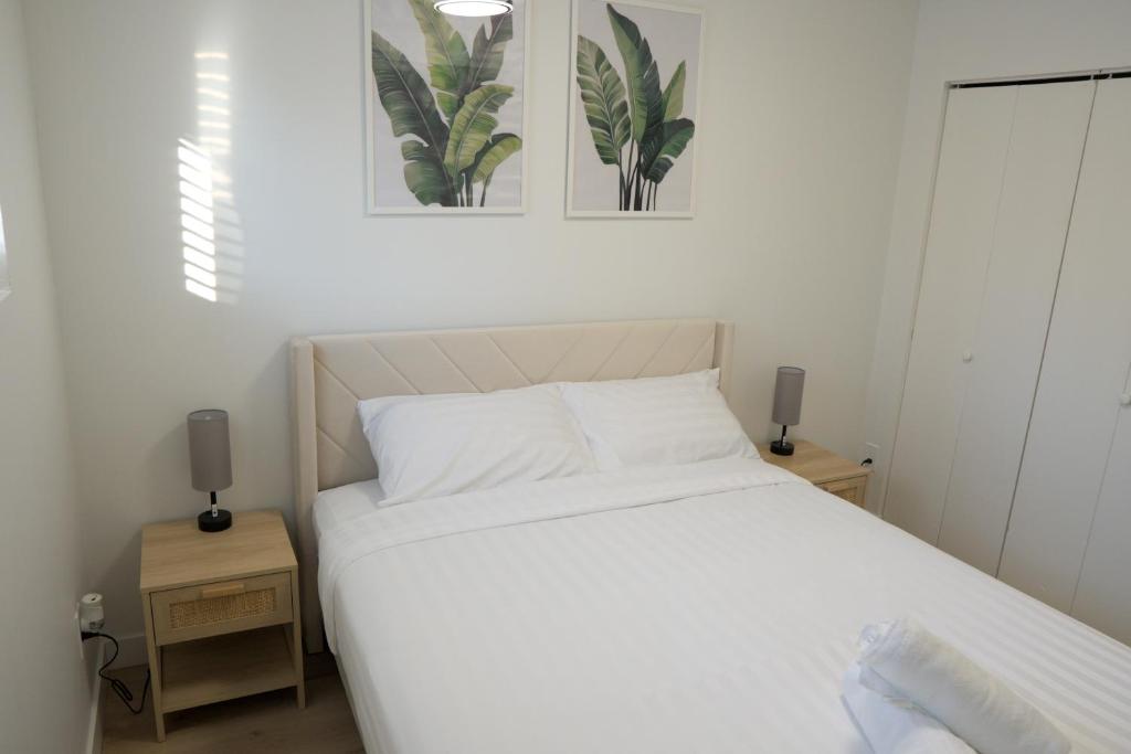 een slaapkamer met een wit bed en twee nachtkastjes bij Sunny Suite in Saskatoon