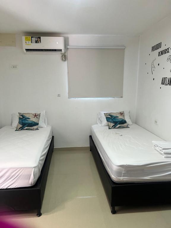 twee bedden in een kamer met witte muren bij kalani cabin in Ríohacha