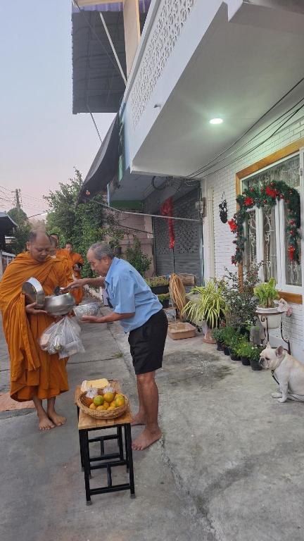 een man staat naast een vrouw met een fruitschaal bij Kan Haven Homestay in Kanchanaburi