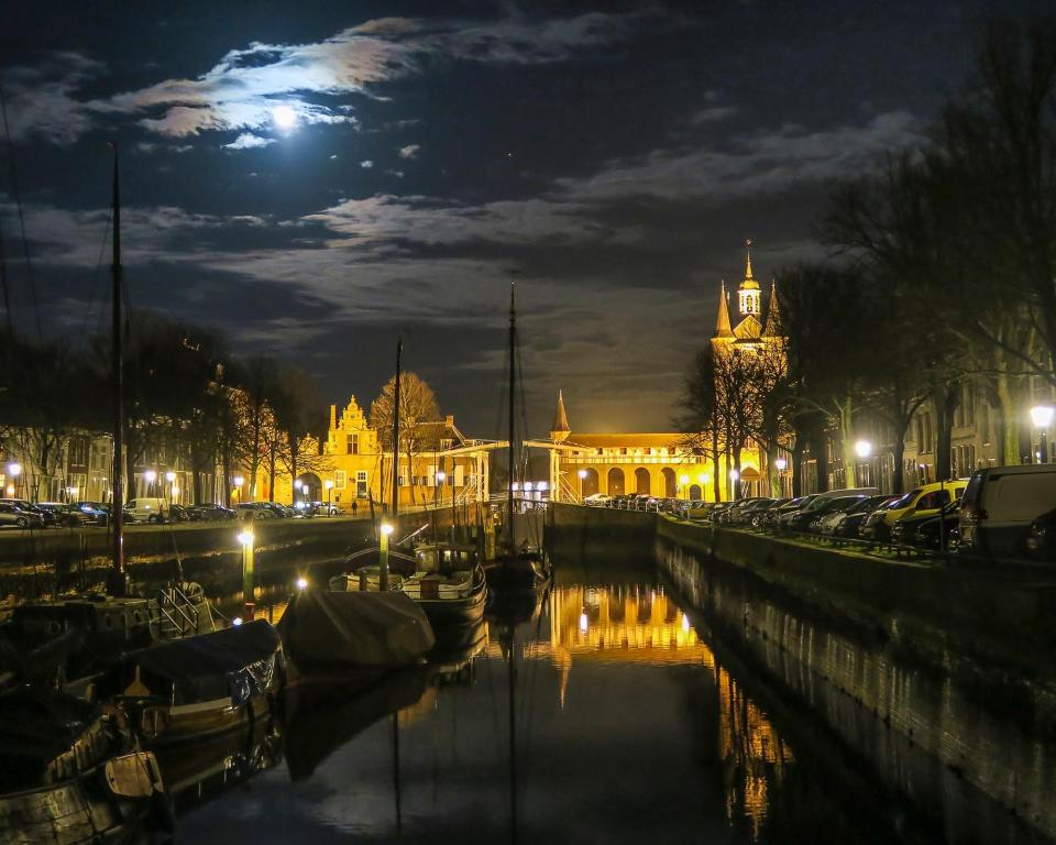 a city lit up at night with a clock tower at De Oude Haven in Zierikzee