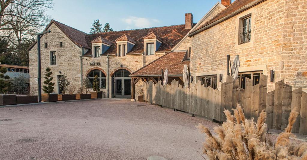 un gran edificio de ladrillo con una valla delante en La Rotisserie du Chambertin, en Gevrey-Chambertin