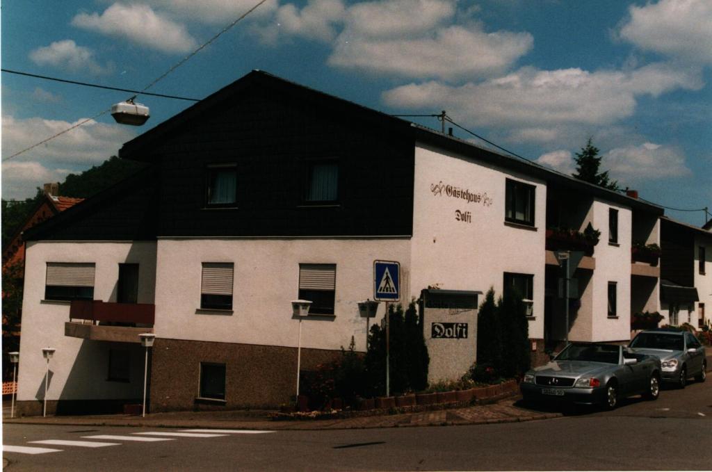un edificio blanco y negro con coches estacionados frente a él en Dolfi Hotel & Restaurant, en Sulzbach