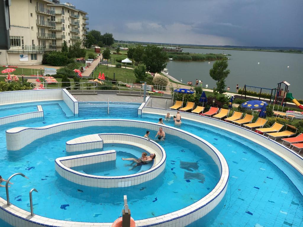 a large swimming pool with people in the water at Aqua Apartman Panoráma in Velence