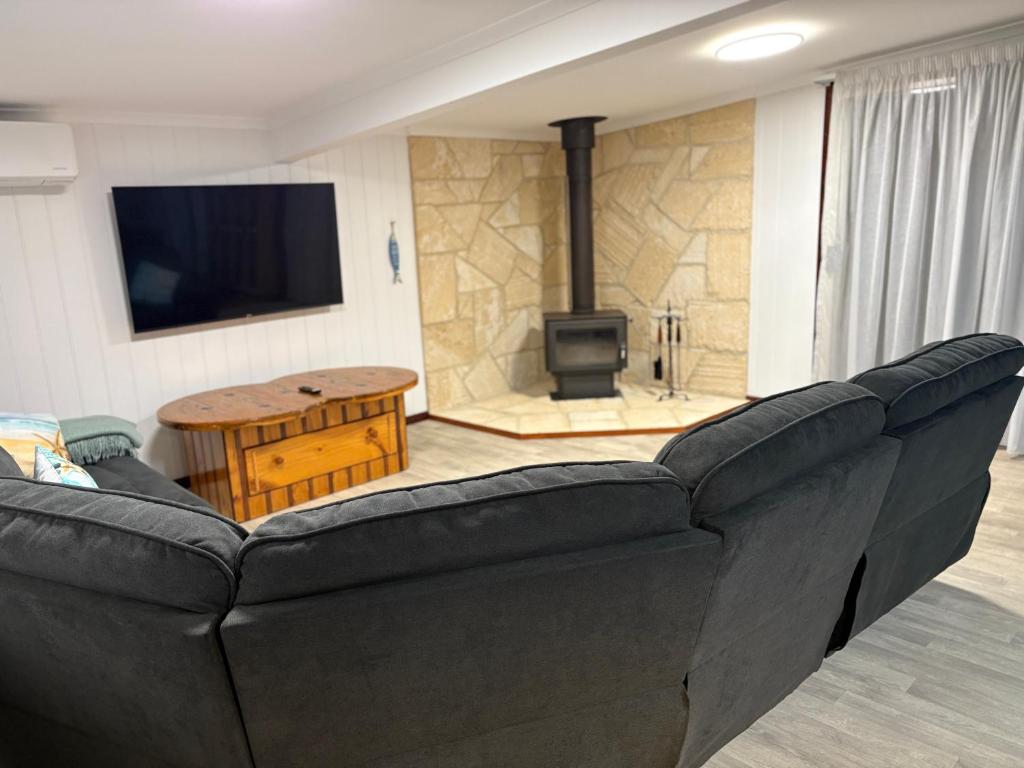 a living room with a black couch and a fireplace at Rustic Retreat Esperance in Esperance