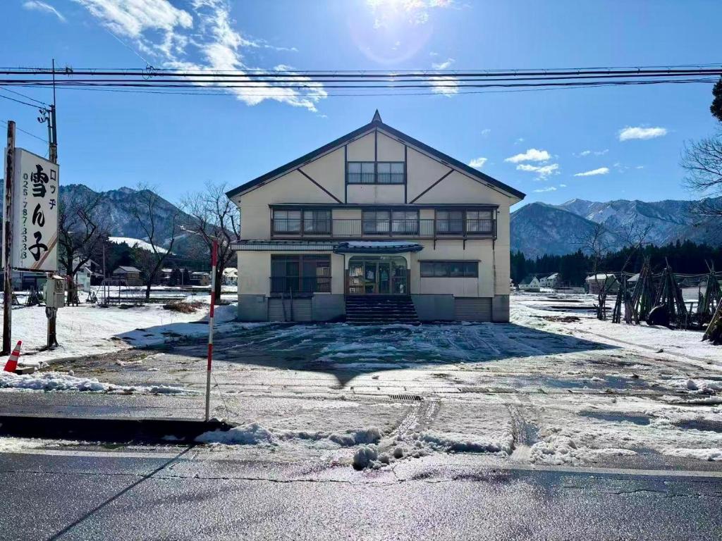 a building in the snow with mountains in the background at ロッヂ 雪ん子 in Yuzawa
