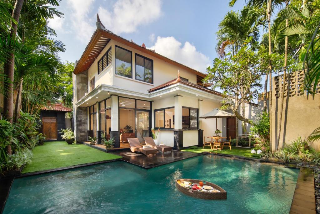 a house with a swimming pool in front of a house at Red Lotus Seminyak Villa in Seminyak