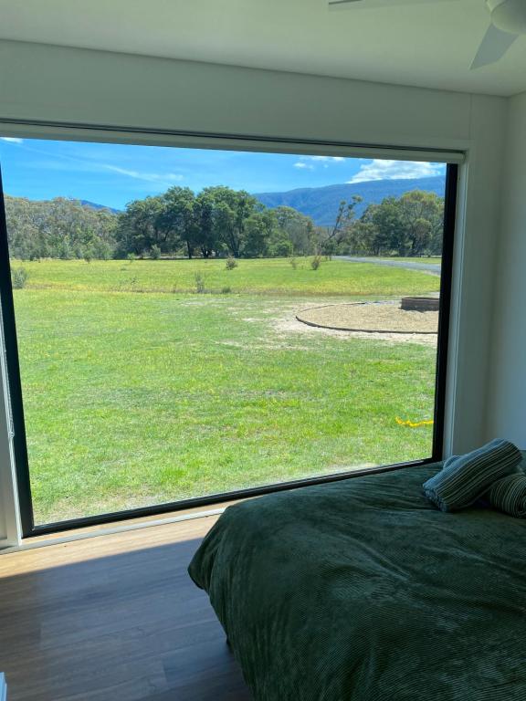 a bedroom with a large window looking out at a field at Grampians View Eco Retreat in Halls Gap