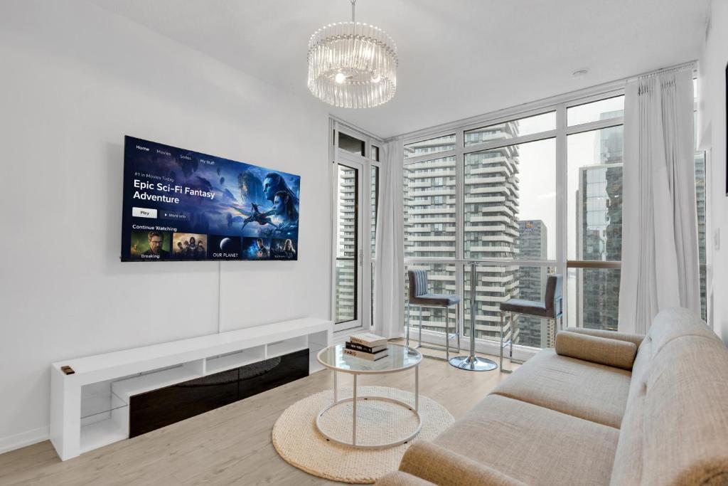 a white living room with a couch and a tv at Luxe 3-Bedroom Lakeview Condo, Free parking ,Walk to CN Tower, Scotiabank Arena & Rogers Centre in Toronto