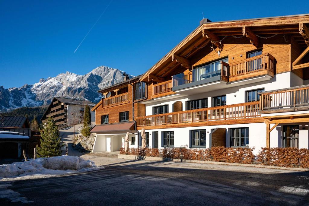 een groot houten gebouw met bergen op de achtergrond bij Tauernlodge Sonnblick Top 2 in Mühlbach am Hochkönig