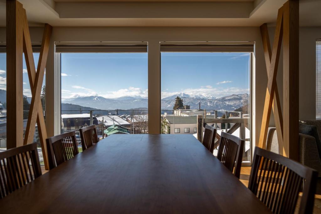 a large dining room table with a view of the mountains at Bella Vista Ski Lodge in Nozawa Onsen