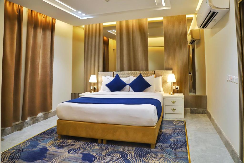 una camera da letto con un letto grande con cuscini blu di رمادا نيت للشقق المخدومة a Tabuk