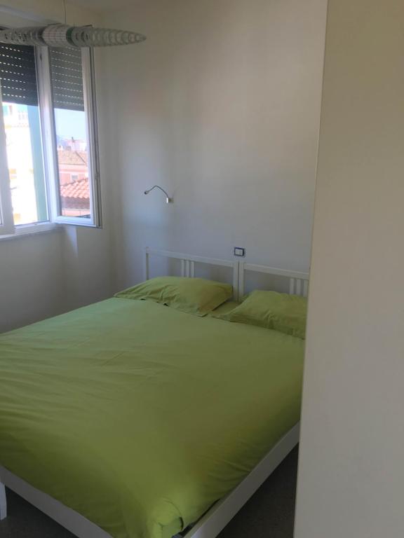 a bedroom with a bed with green sheets and a window at Casa Maria in Salerno