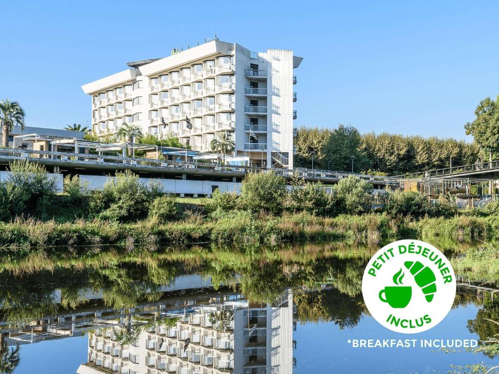 een gebouw naast een rivier met een reflectie in het water bij ibis styles Dax Centre in Dax