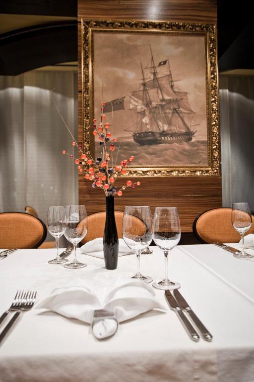 a table with wine glasses and a picture of a ship at Hotel Odissey Jaz in Budva