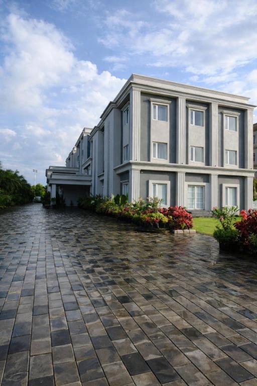 a large apartment building with a stone driveway at La Franklin Hotel in Parādīp Garh