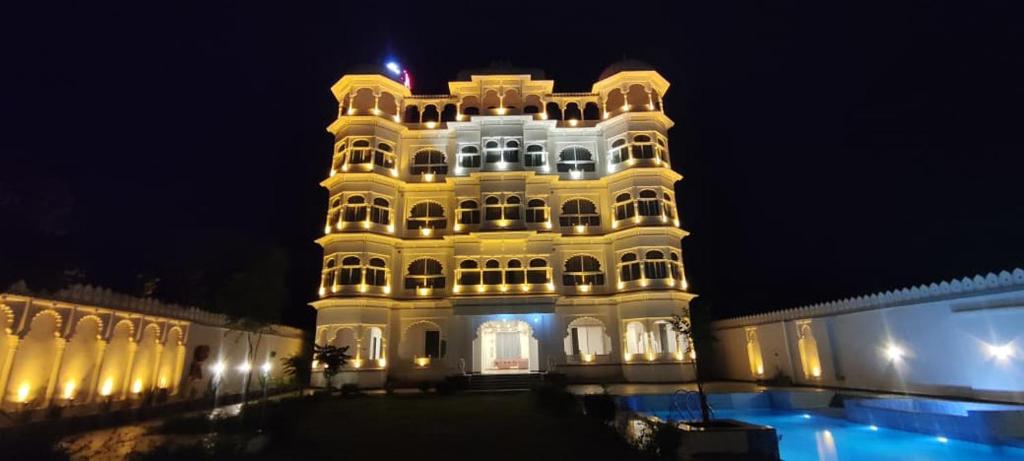 un grand bâtiment avec une tour la nuit dans l'établissement Omnitel Kohinoor, à Udaipur