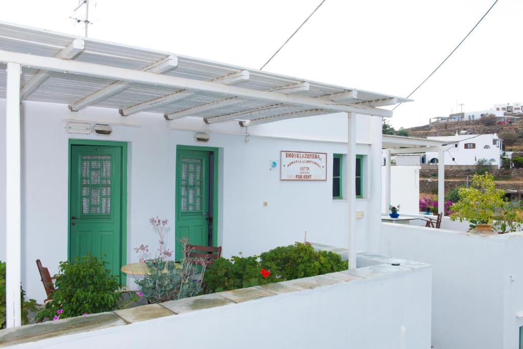 a white house with green doors and a pergola at Letta Studios in Apollonia