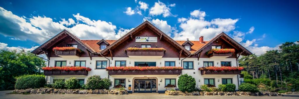 een groot gebouw met bloemen ervoor bij Hotel Restaurant Schwartz in Neusiedl am Steinfelde