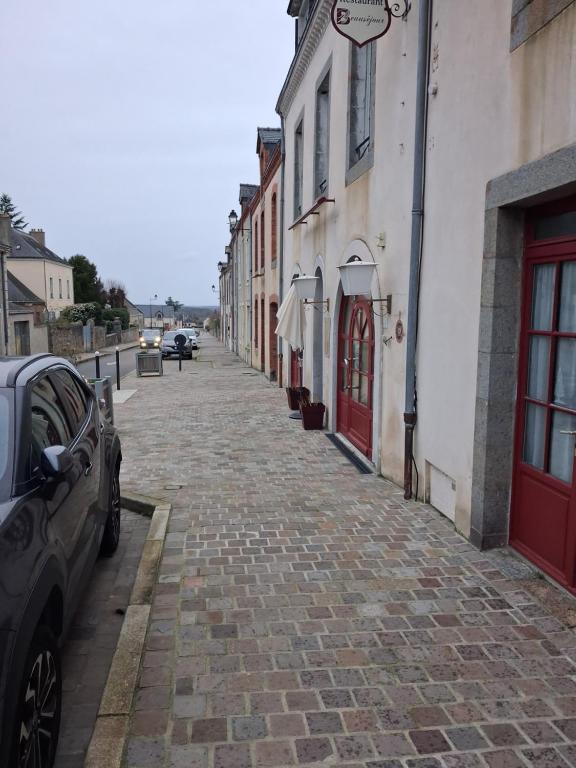 a cobblestone street next to a building with red doors at Hôtel le beau séjour in Sainte-Suzanne