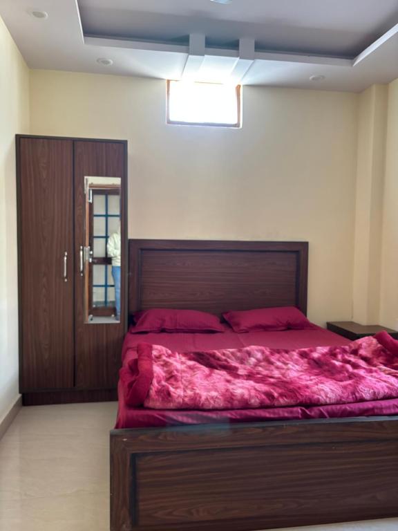 a bedroom with a large bed with red sheets at Hathayogashram Hostel in Rishīkesh