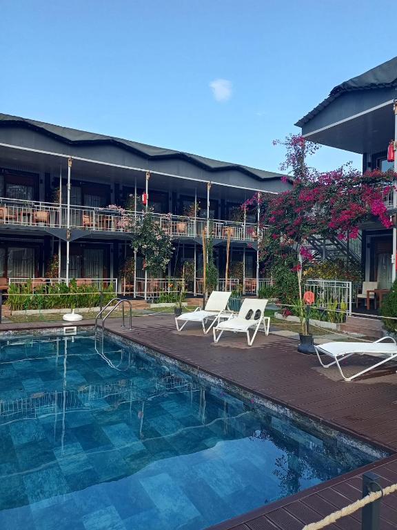 a resort with a swimming pool and chairs and a building at Fİi SUİTES in Kumluca