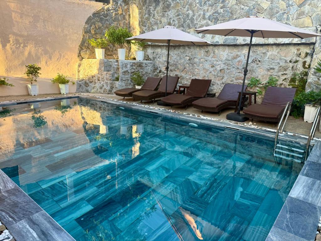 ein großer Swimmingpool mit Liegen und Sonnenschirmen in der Unterkunft Villa Khili Phousi in Luang Prabang