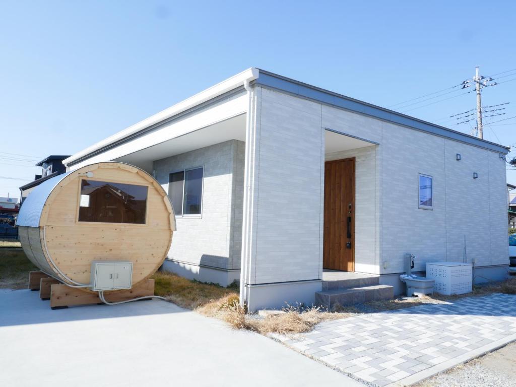 a small house with a large wooden circle next to it at 9Stay伊勢崎 in Isesaki