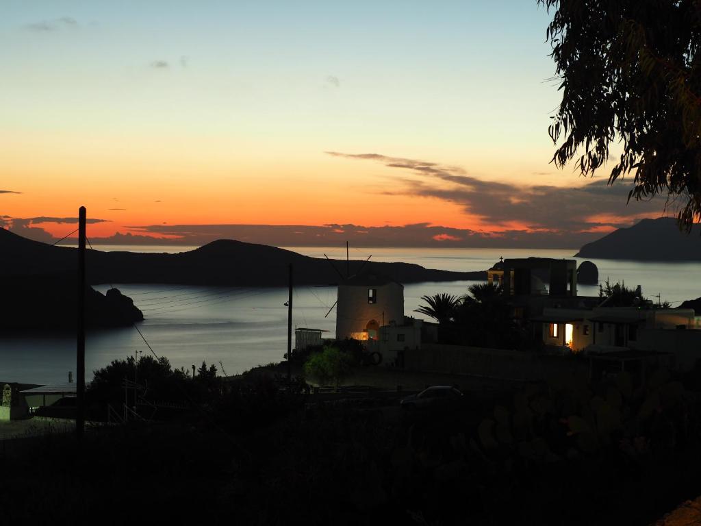a sunset over a body of water with a house at Anastasia's windmill and Anastasia's studio in Plaka Milou